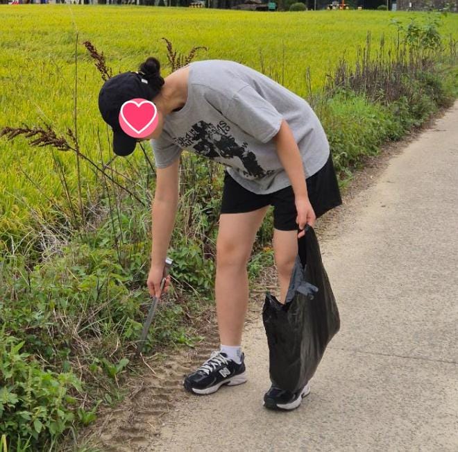 논길 가장자리에서 집게로 쓰레기를 집는 모습