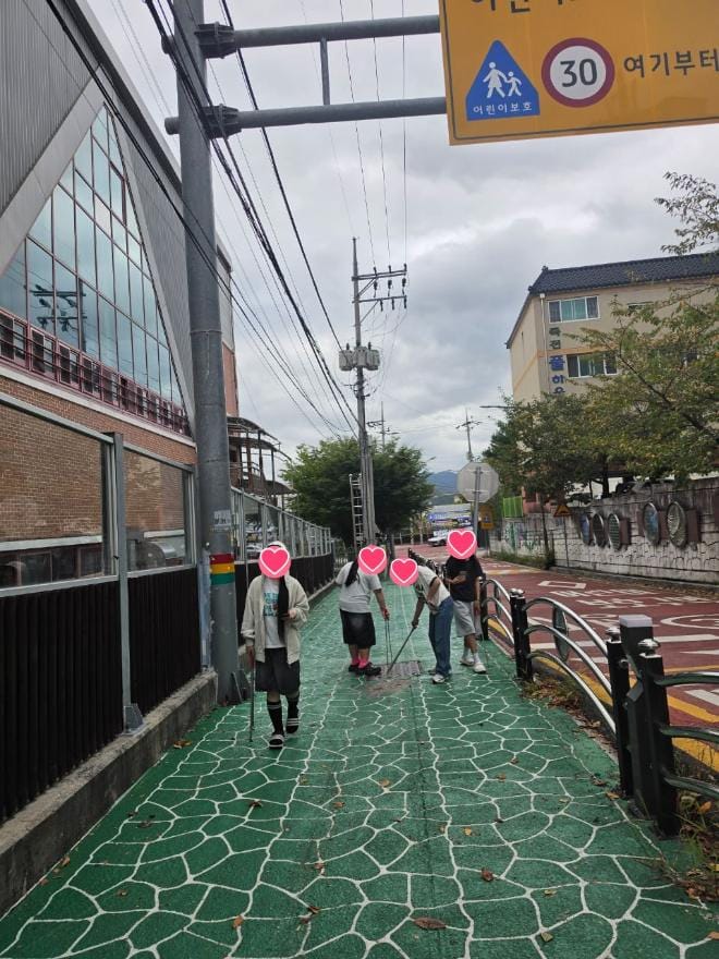거창읍 학교 앞 보도에서 청소년들이 집게로 쓰레기를 줍고 있는 모습