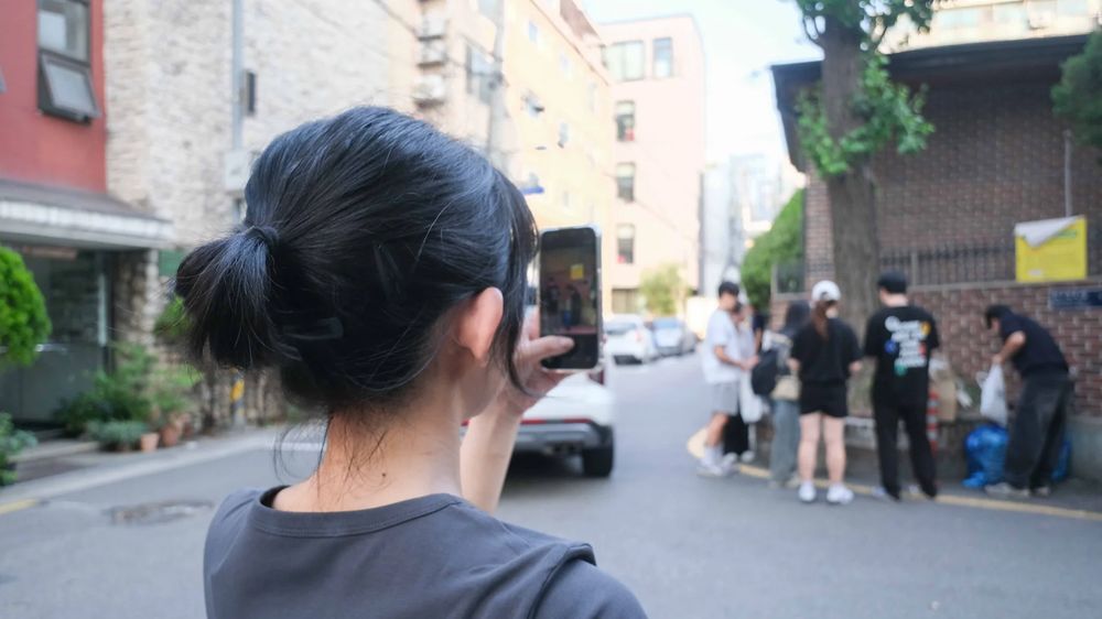 골목에서 휴대폰으로 길거리를 찍어 기록하는 사람